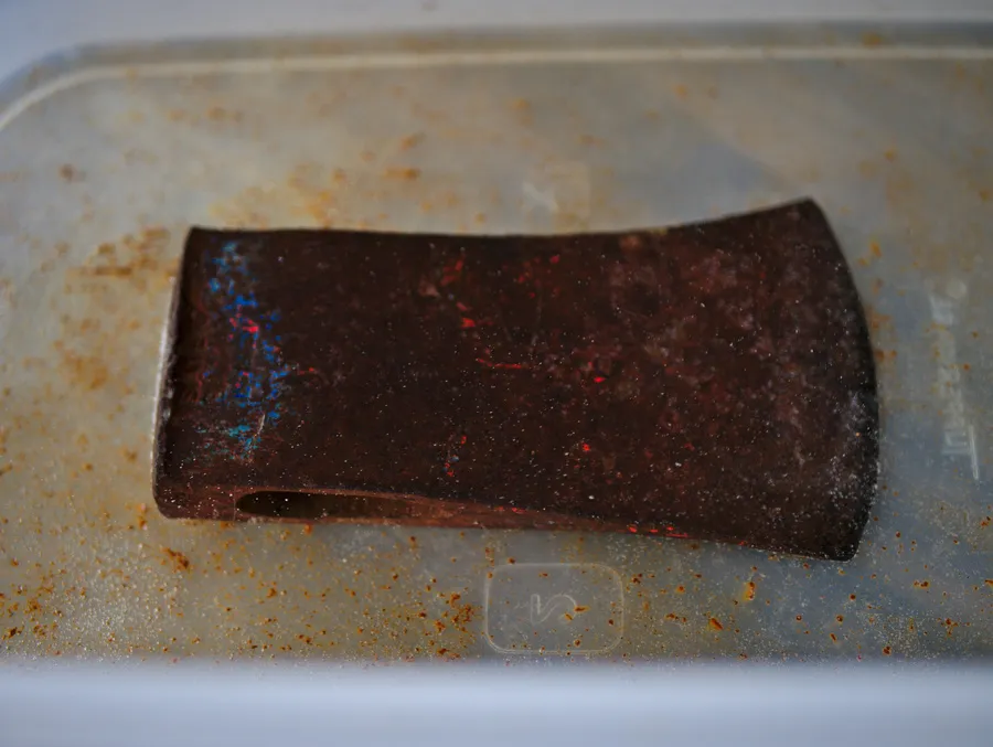 Hatchet head after a vinegar bath and wire-brush scrubbing, old blue paint showing through